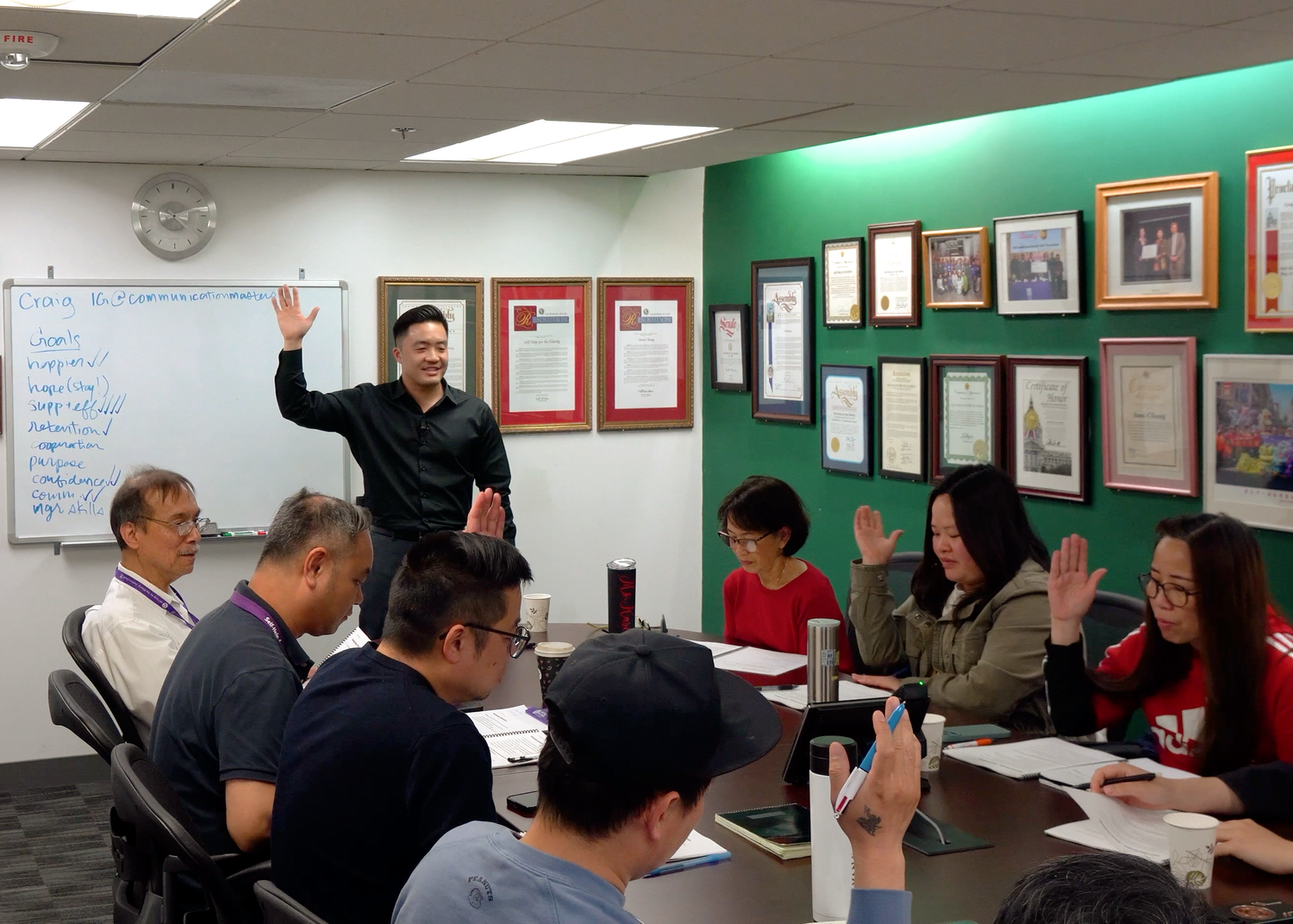 Craig Chee facilitating an interactive training session, with participants raising hands to answer a discussion question